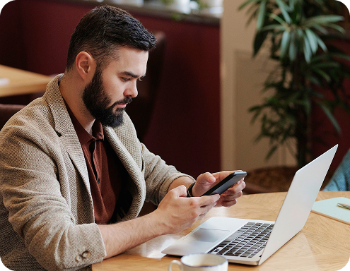 Restaurant owner reviewing orders on a phone and laptop